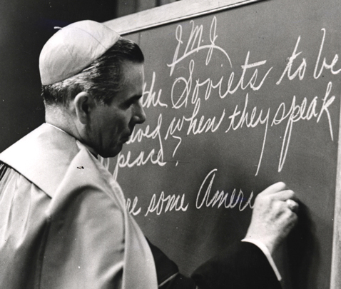 Fulton Sheen writing on a blackboard